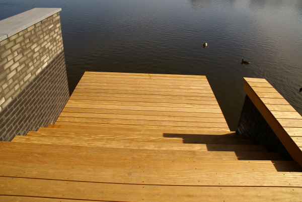 Tuin aan het water met strakke lijnen, keramiek tegels en vlonders met trap DECAtuinen hoveniers Almere Flevoland
