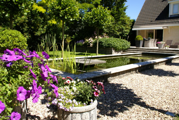 Tuin met natuurstenen bestrating, groot terras, strak lijnenspel, vijver, veranda en zwembad DECAtuinen Almere Flevoland
